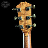 Close-up of the headstock of a Taylor guitar, showing six tuning pegs and the brand name on each peg, set against a solid black background.