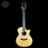 A Taylor acoustic-electric guitar with a natural wood finish and black cutaway body, shown against a solid black background with a Tone Shop watermark in the top-left corner.