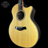 A Taylor acoustic-electric guitar with a natural wood top and black sides, shown against a solid black background with a Tone Shop watermark in the top left corner.