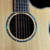 Close-up of a Taylor acoustic guitar body showing the natural wood grain, sound hole, and iridescent abalone inlay rosette.