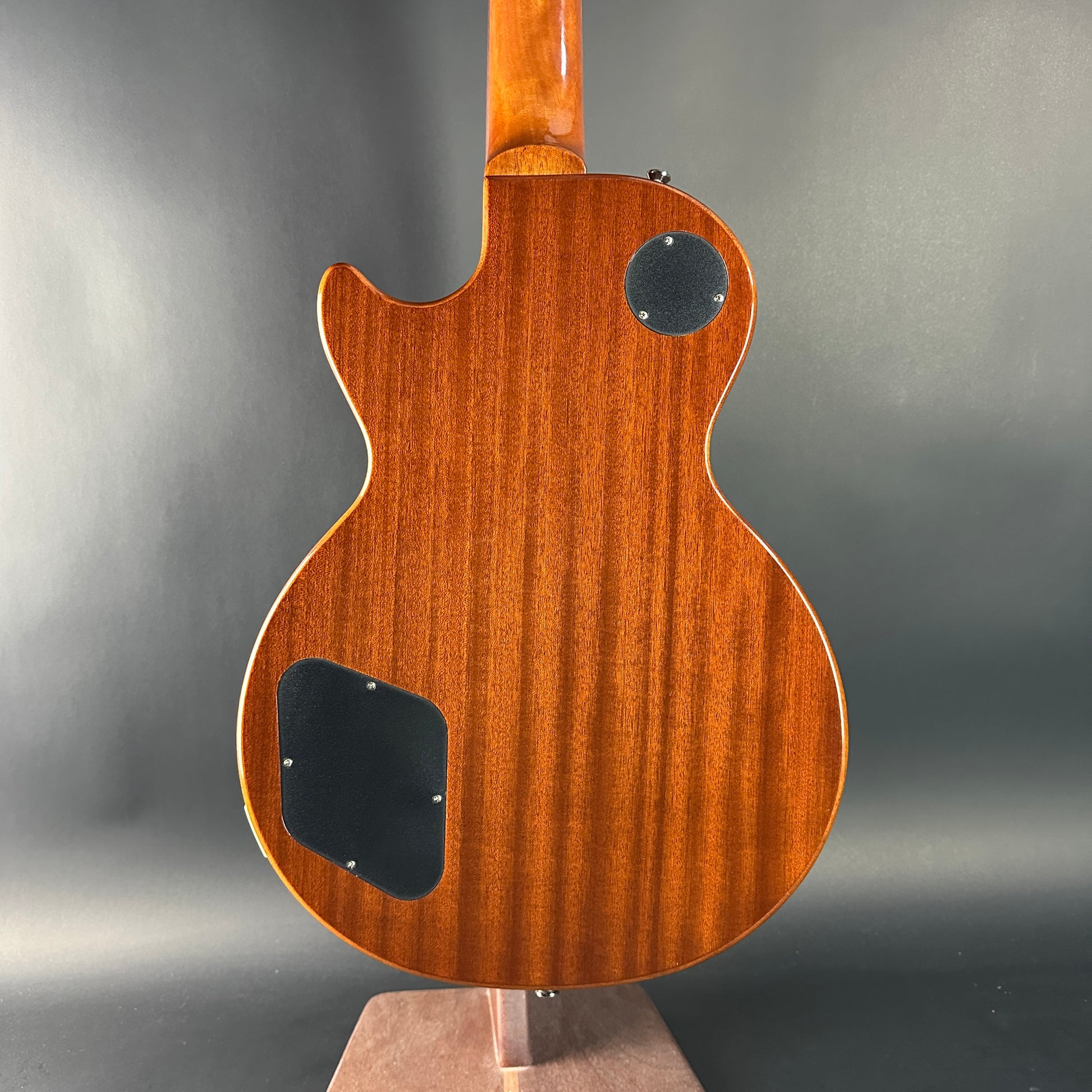 Back view of a wooden electric guitar on a gray background