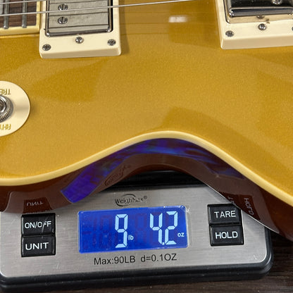 Gold electric guitar on a digital scale displaying weight.