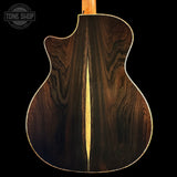 The back of an acoustic guitar made of dark brown wood with a prominent central light wood inlay, shown against a solid black background. A 'TONE SHOP' watermark is visible in the top-left corner.