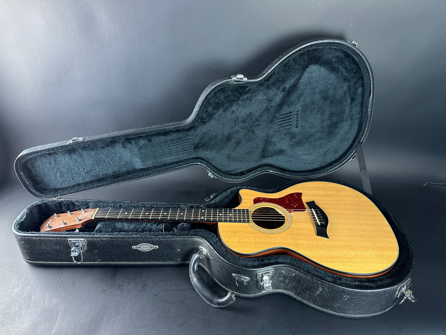 Acoustic guitar in an open hardshell case on a gray background