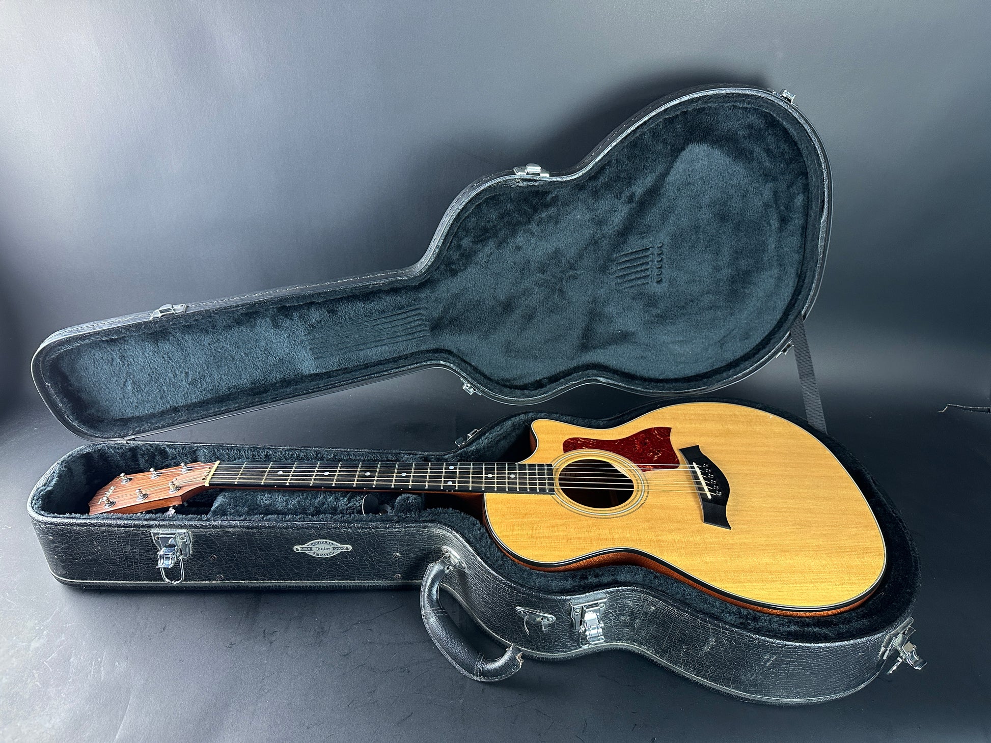 Acoustic guitar in an open hardshell case on a gray background