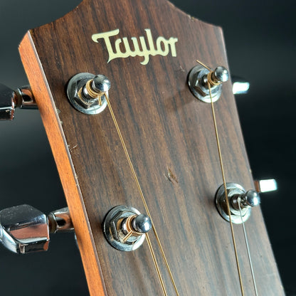 Close-up of a Taylor guitar headstock with tuning pegs and brand name.