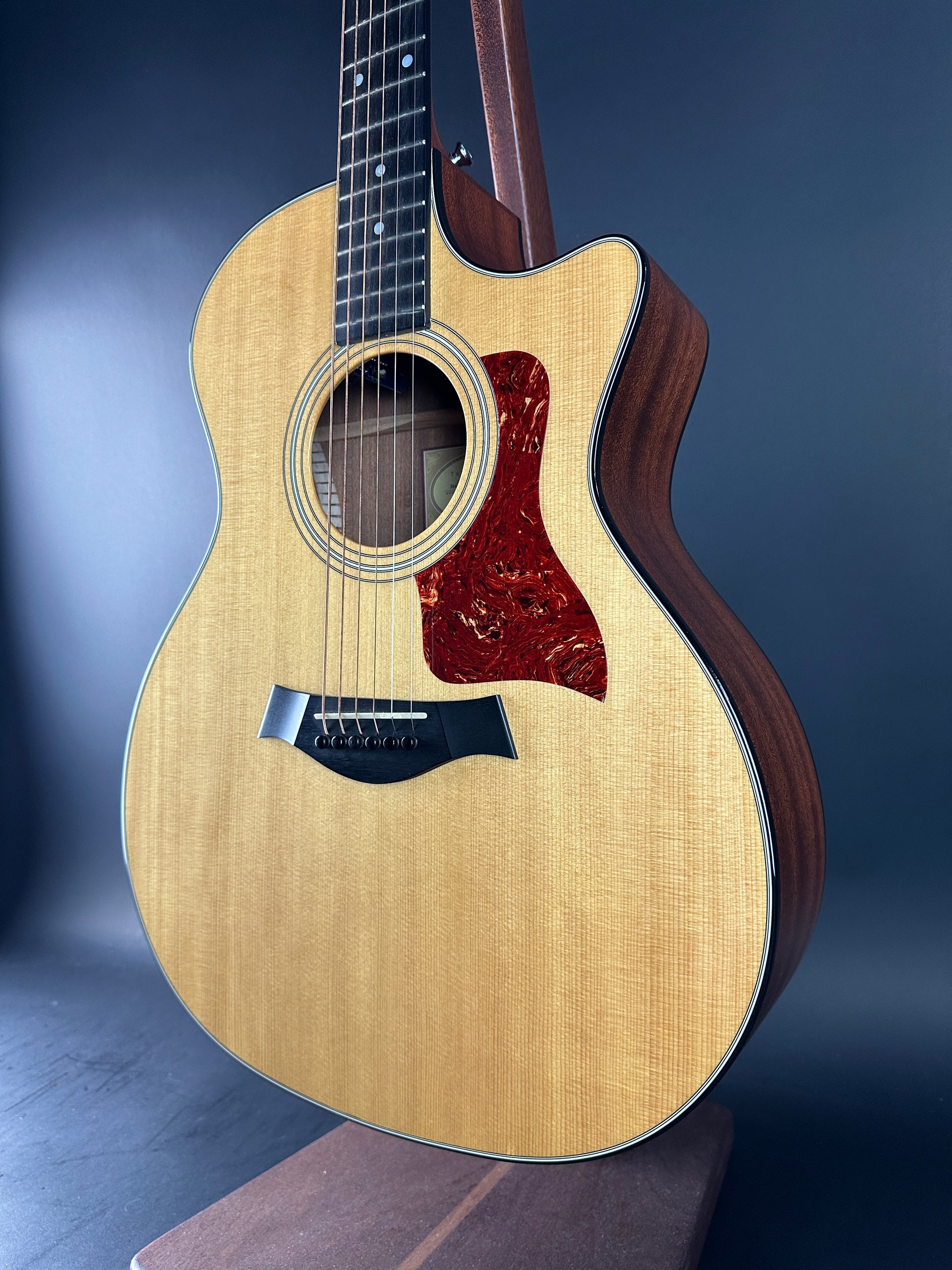 Acoustic guitar with a wooden body and dark brown neck on a dark background