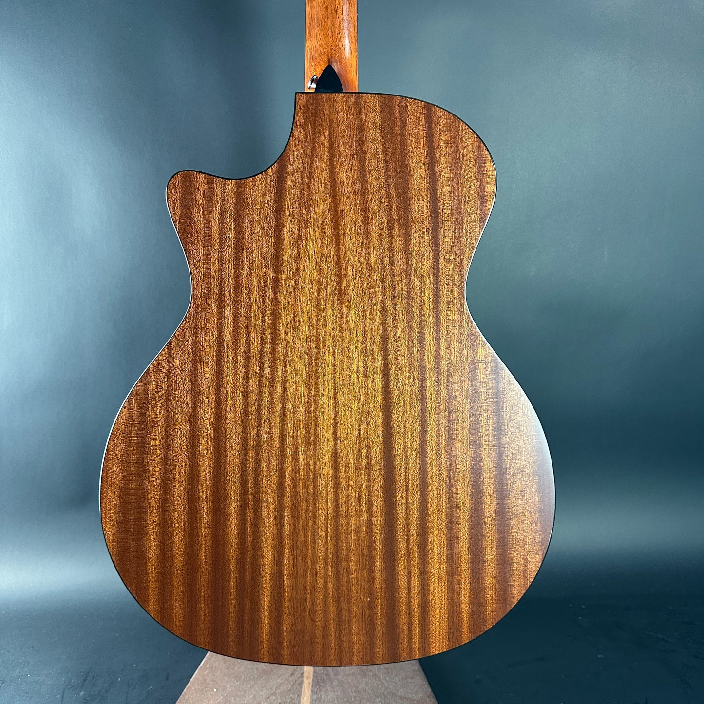 Back view of a wooden acoustic guitar on a gray background