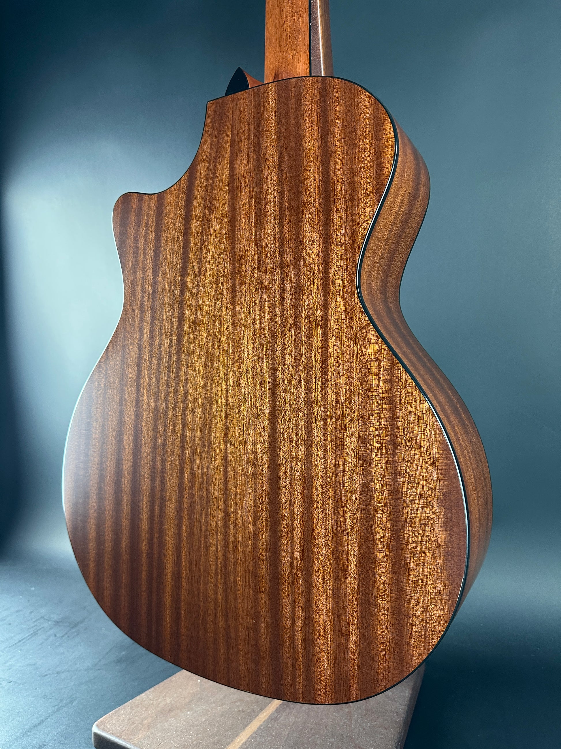 Close-up of a wooden guitar body with a dark blue background