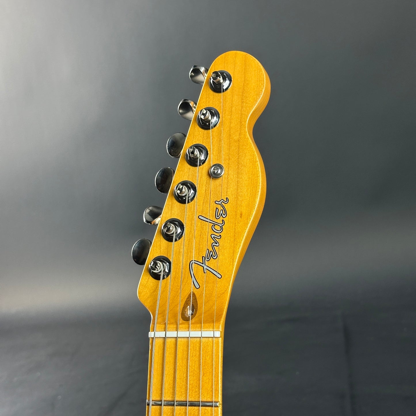 Guitar headstock with Fender logo on a gray background