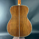 Back view of a wooden acoustic guitar on a dark gray background