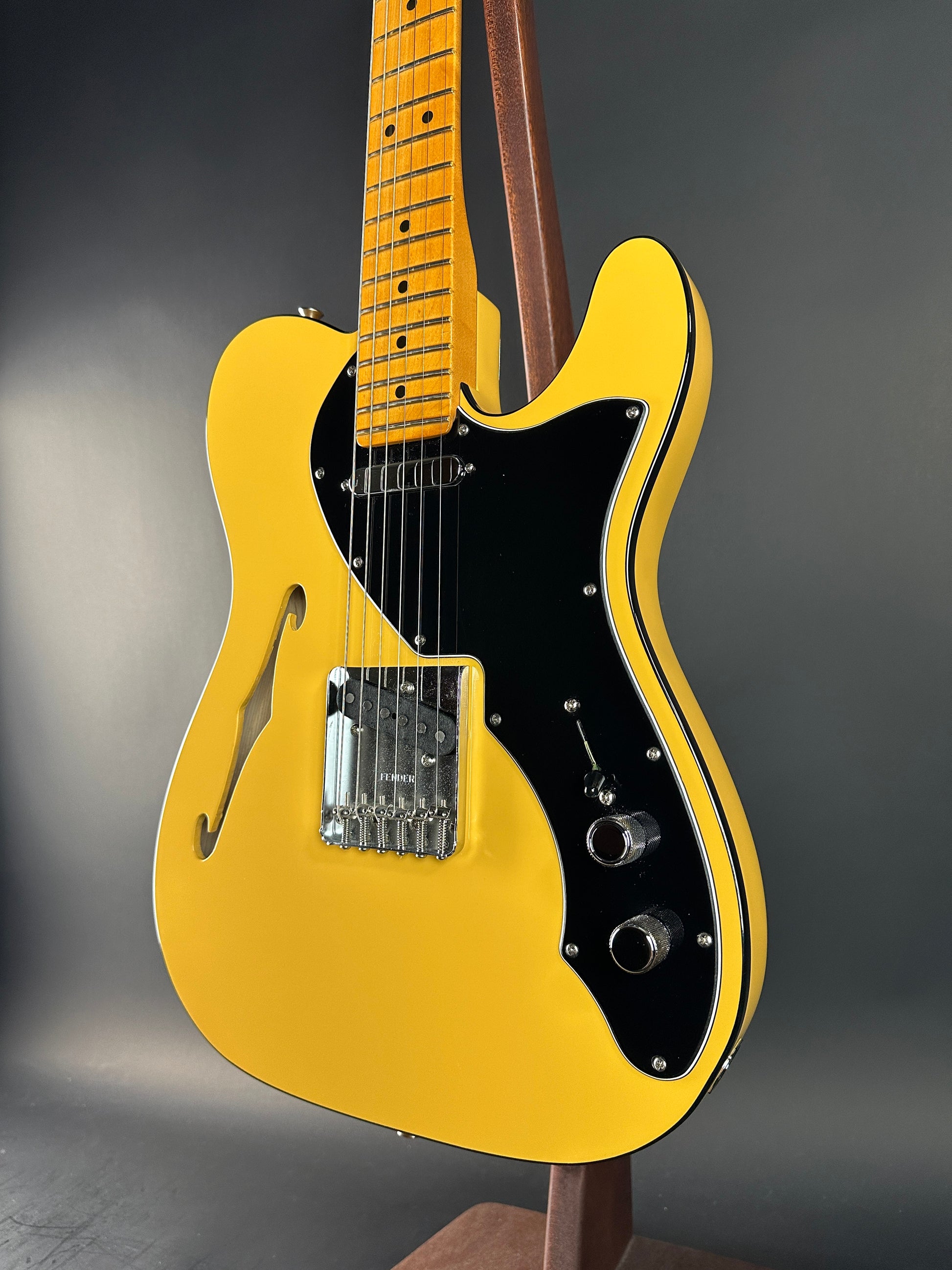 Yellow electric guitar with a black pickguard on a dark gray background