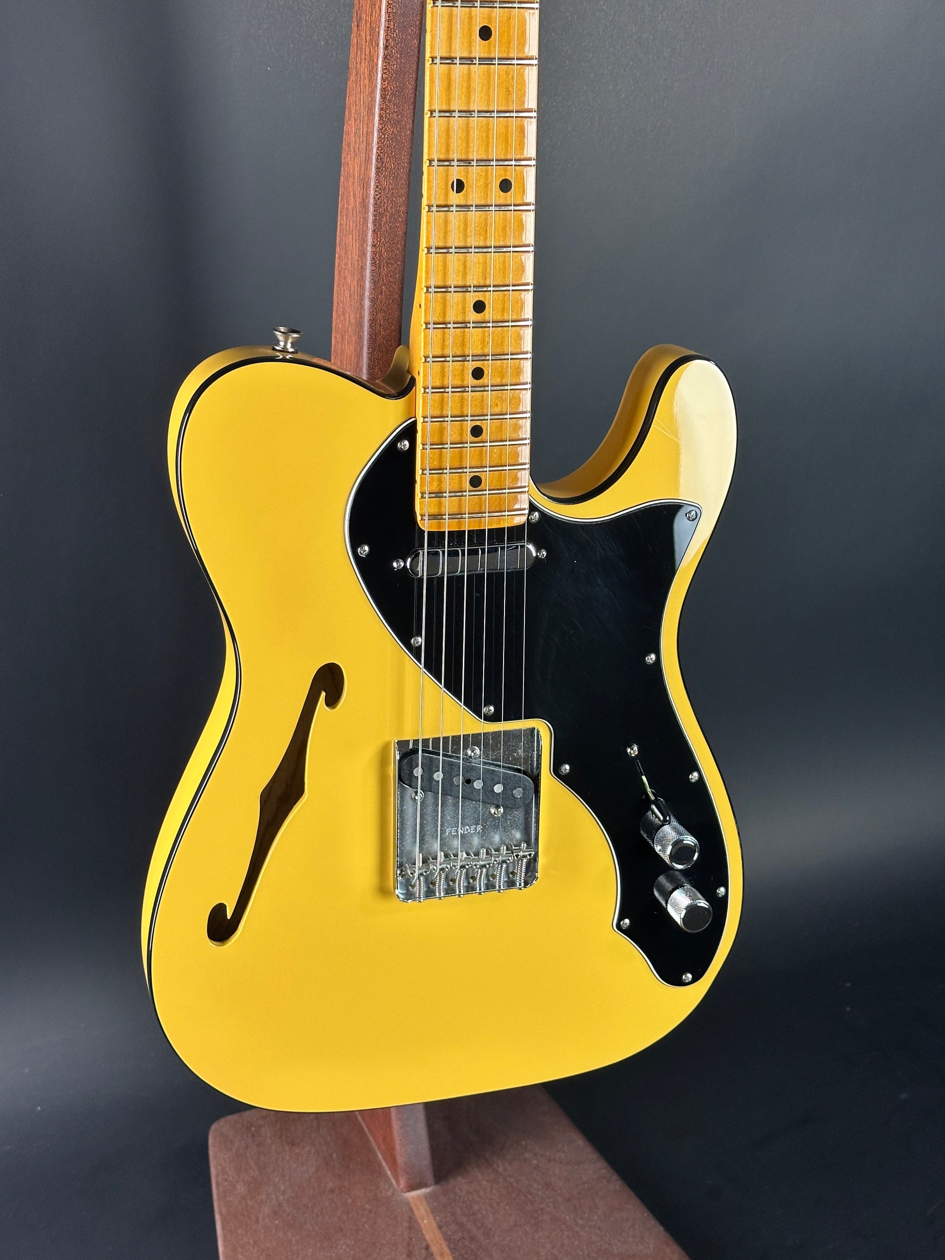 Yellow electric guitar with a black pickguard on a dark background