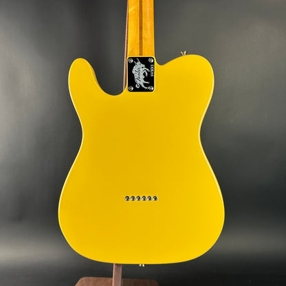 Yellow electric guitar on a stand with a dark background