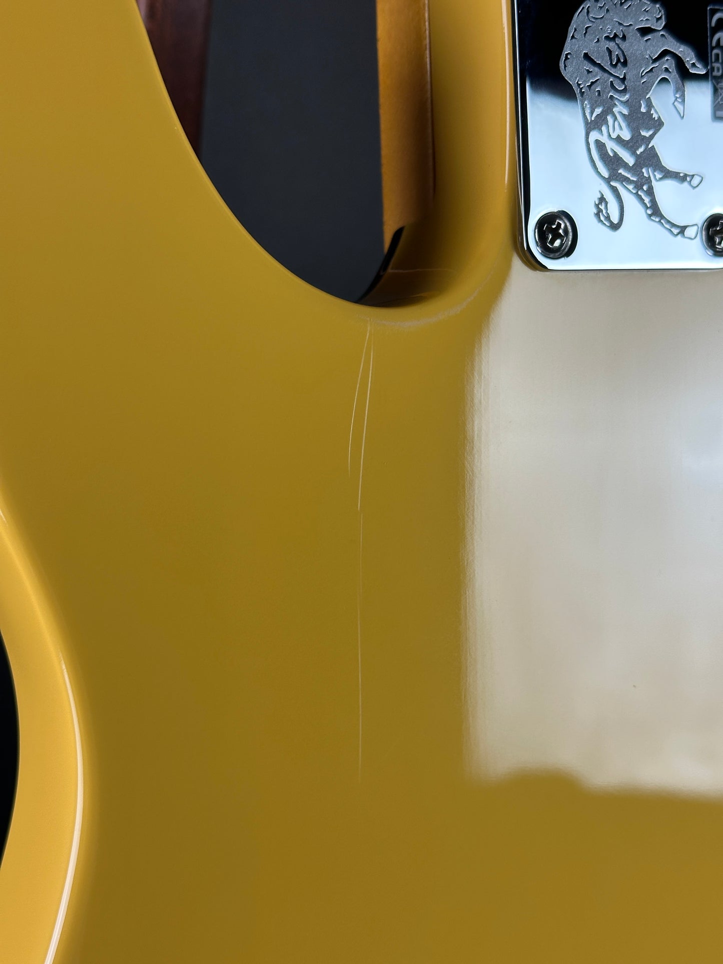 Close-up of a yellow guitar neck with a brand logo on the headstock.