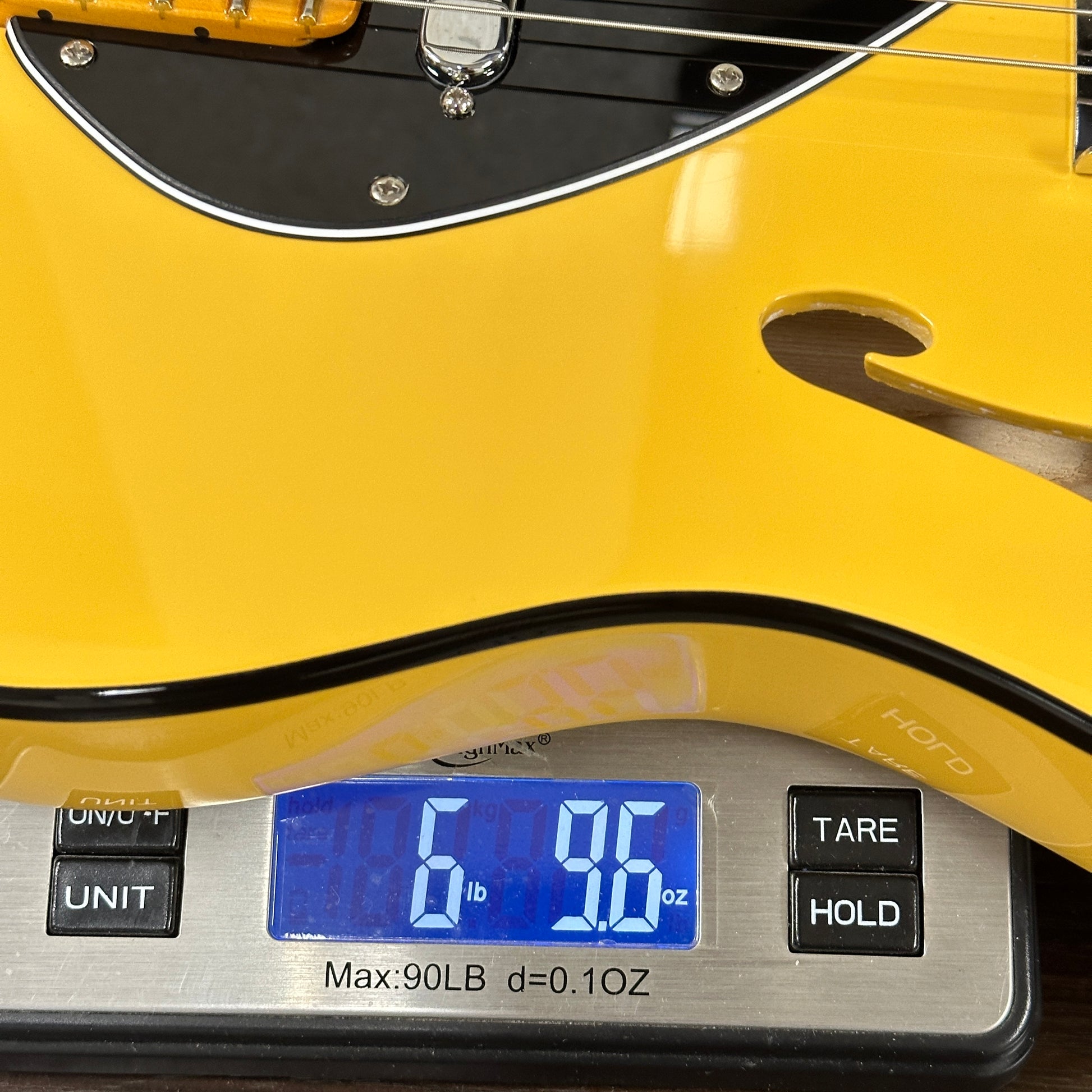 Yellow electric guitar on a digital scale displaying weight