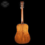 The back of an acoustic guitar with a rich, warm brown wood finish and visible grain patterns, photographed against a solid black background. A 'TONE SHOP' watermark is visible in the top-left corner.