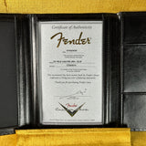 A Fender Certificate of Authenticity card displayed inside an open black leather Fender case, with a gold velvet surface visible at the top and bottom.