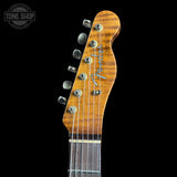 Close-up of the headstock of a Fender electric guitar, showing the wood grain, six tuning pegs, and the Fender logo, set against a solid black background.