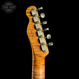 Close-up of the headstock of an electric guitar with a warm orange-brown flamed maple wood finish and silver tuning pegs, set against a solid black background. A Tone Shop watermark is visible in the top left corner.