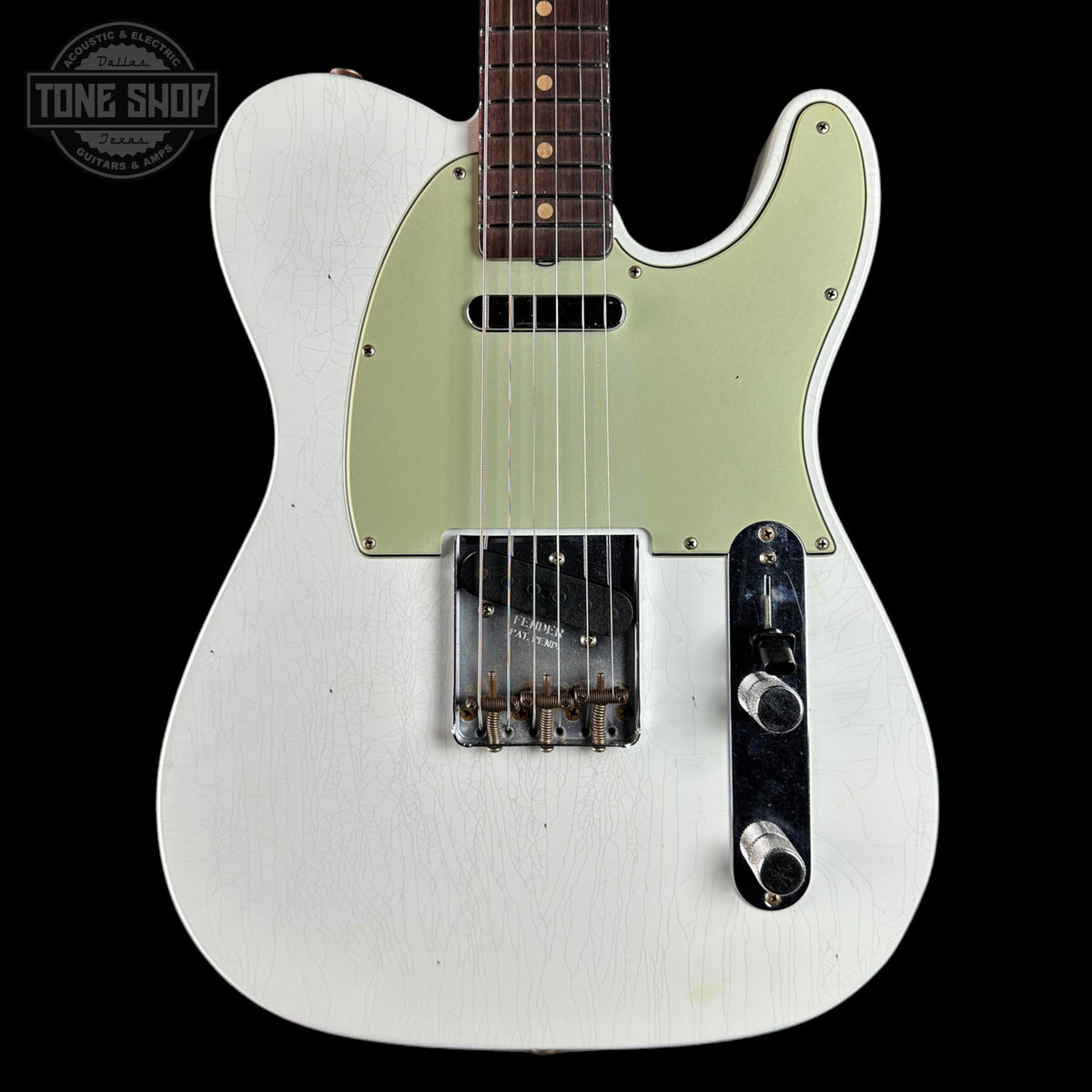 A white Fender Telecaster electric guitar with a light green pickguard and a dark brown maple fretboard, shown against a solid black background. A 'Tone Shop' watermark is visible in the top-left corner.
