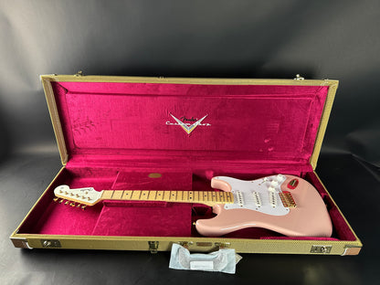 Pink electric guitar in a Fender case on a dark background