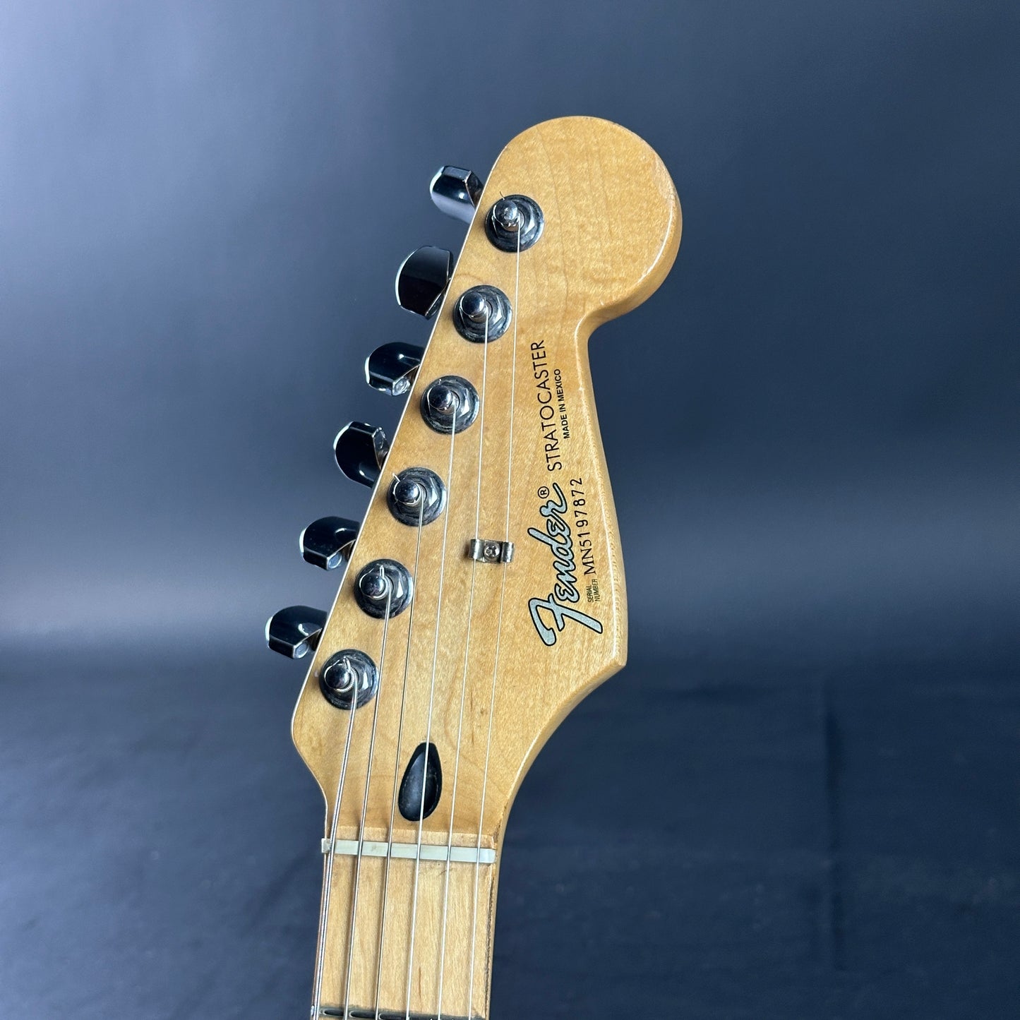 Fender Stratocaster guitar headstock on a dark blue background