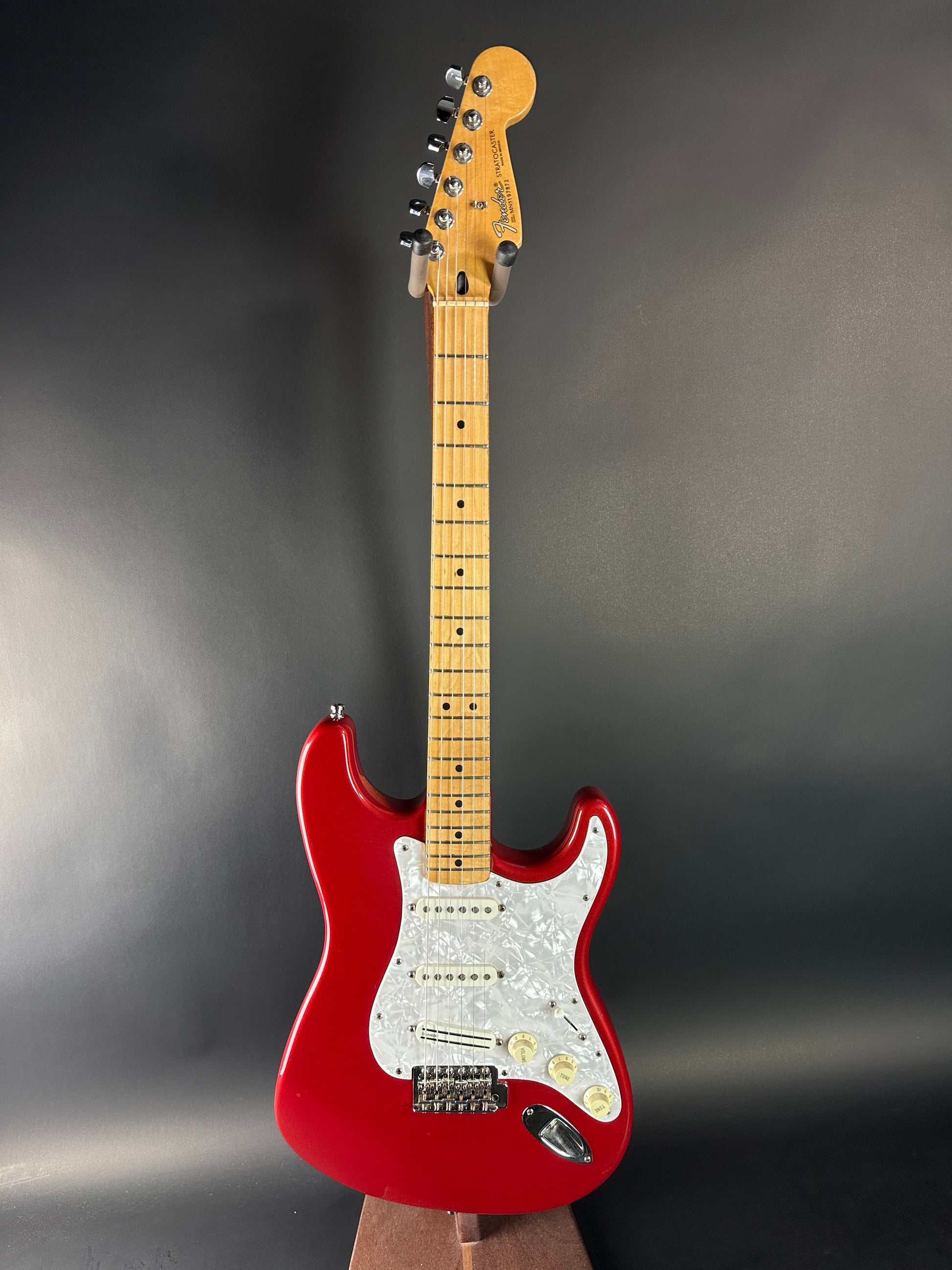 Red electric guitar with a wooden neck on a dark gray background