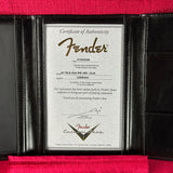 A black leather Fender instrument certificate holder displaying a silver Certificate of Authenticity with the Fender logo, set against a red velvet background.