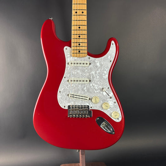 Red electric guitar with a pearl inlay on a gray background