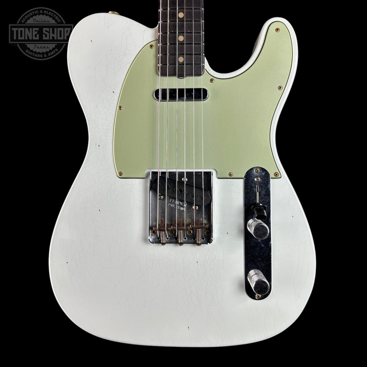 A white Telecaster-style electric guitar with a pale green pickguard, black control plate, and dark fretboard, shown against a black background. A Tone Shop watermark is visible in the top-left corner.