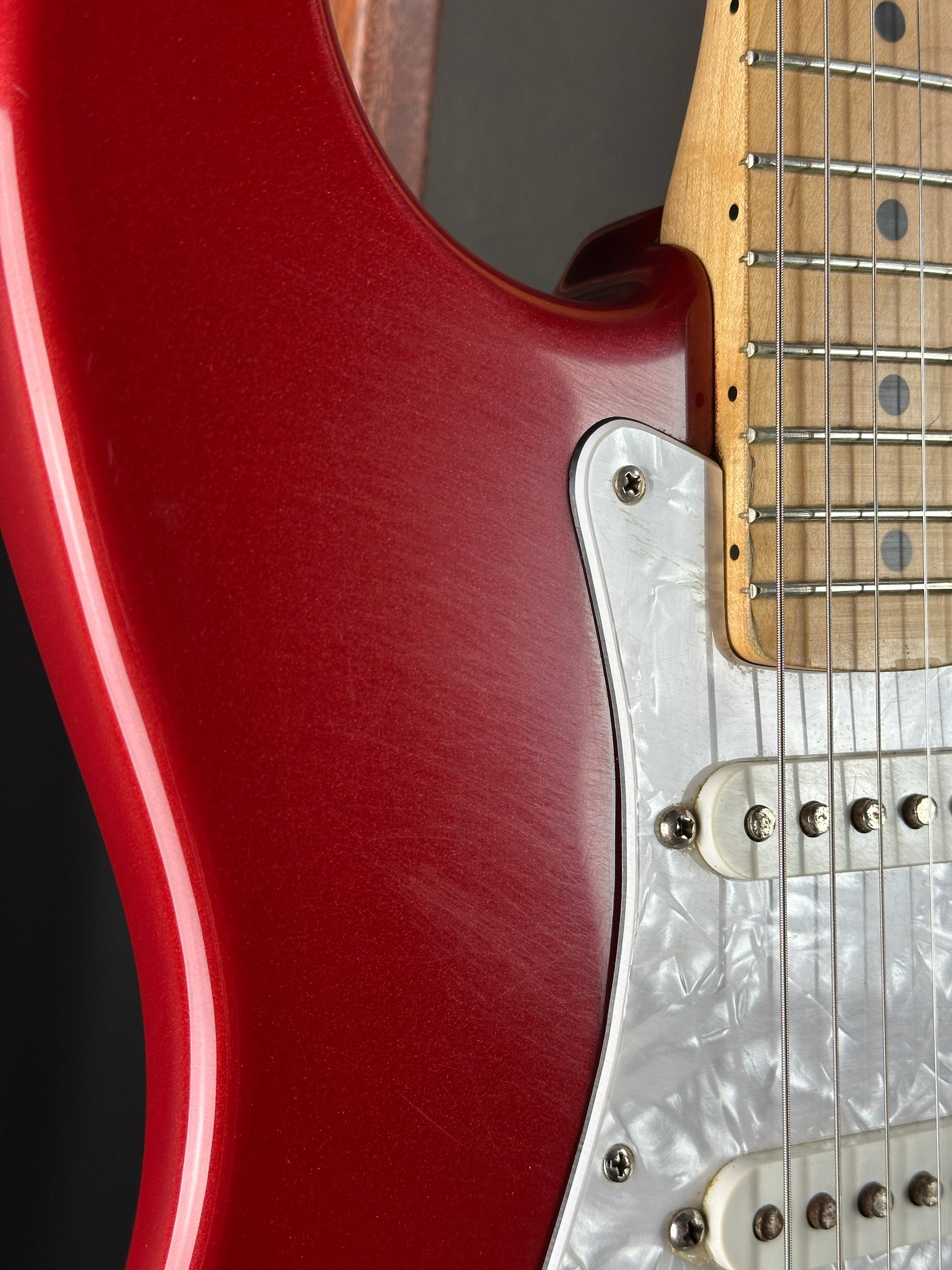 Close-up of a red electric guitar with a focus on the body and neck.