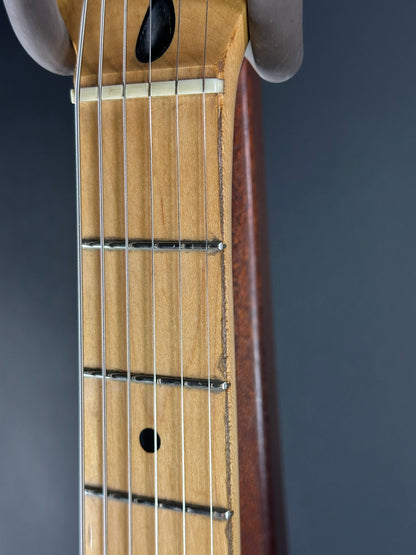 Close-up of a guitar's fretboard and strings against a dark background