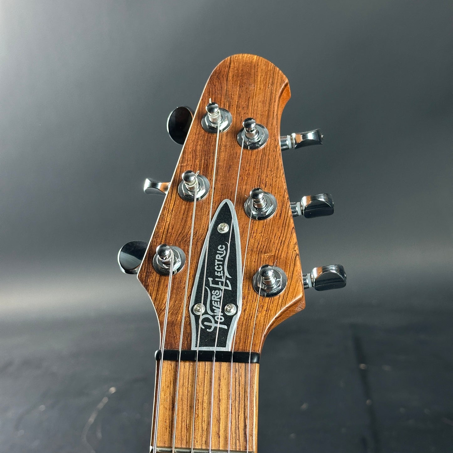 Close-up of a guitar headstock with brand name on a dark background