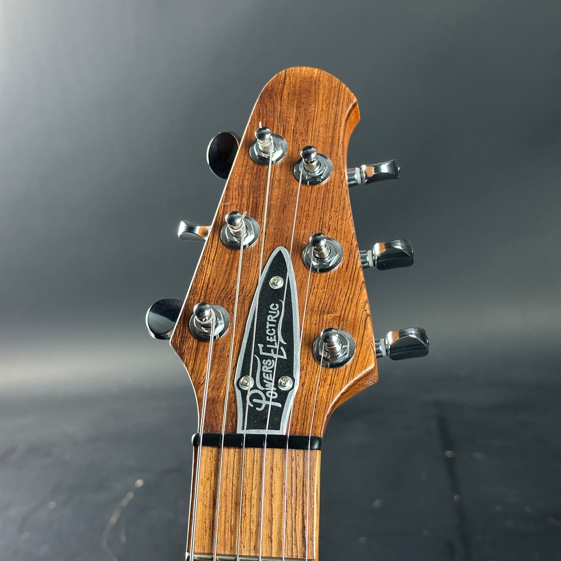 Close-up of a guitar headstock with brand name on a dark background