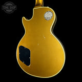 The back of a gold Gibson Les Paul Custom electric guitar with a black pickguard and a visible 'Tone Shop' store watermark in the upper left corner, set against a solid black background.