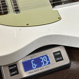 Close-up of a white electric guitar body resting on a digital scale showing 6.39 lbs.