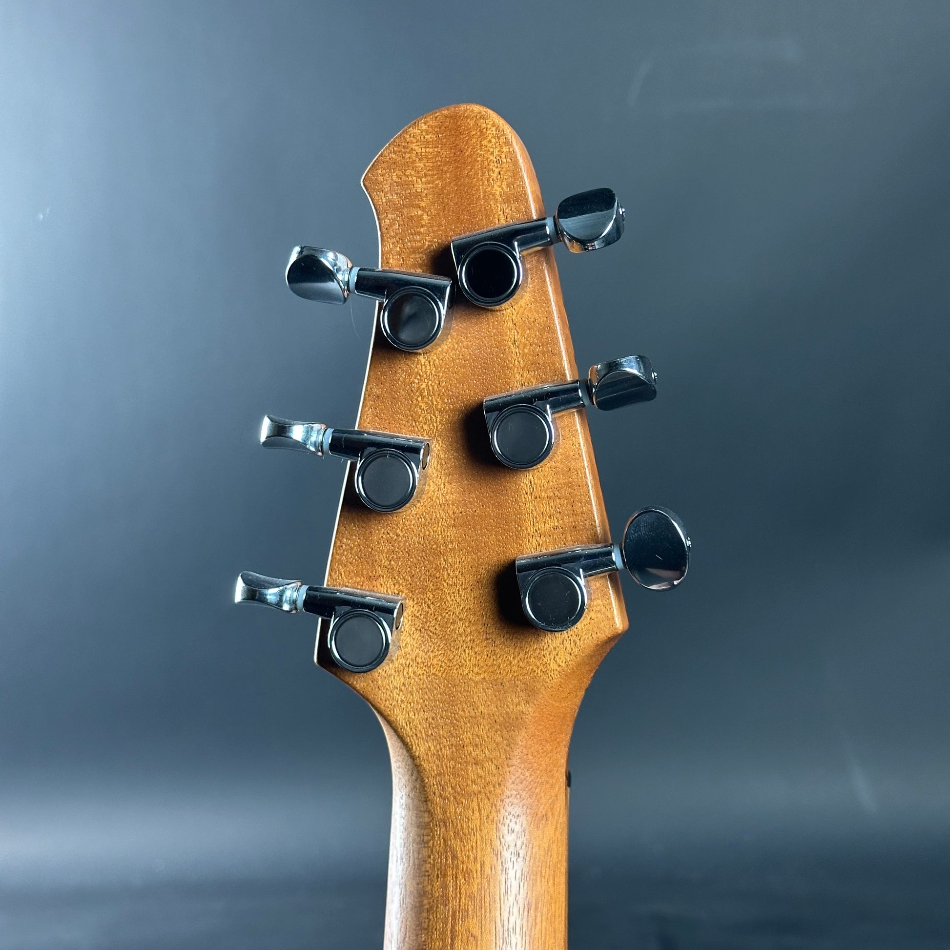 Close-up of a guitar headstock with tuning pegs on a dark background