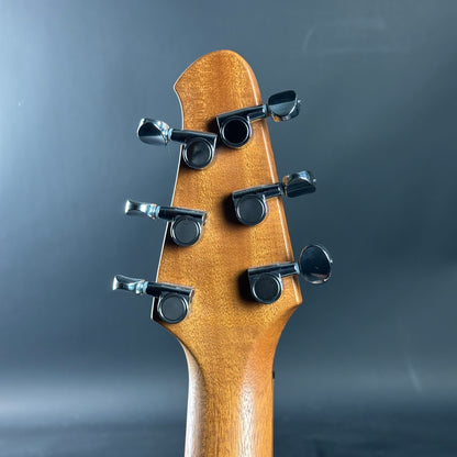 Close-up of a guitar headstock with tuning pegs on a dark background