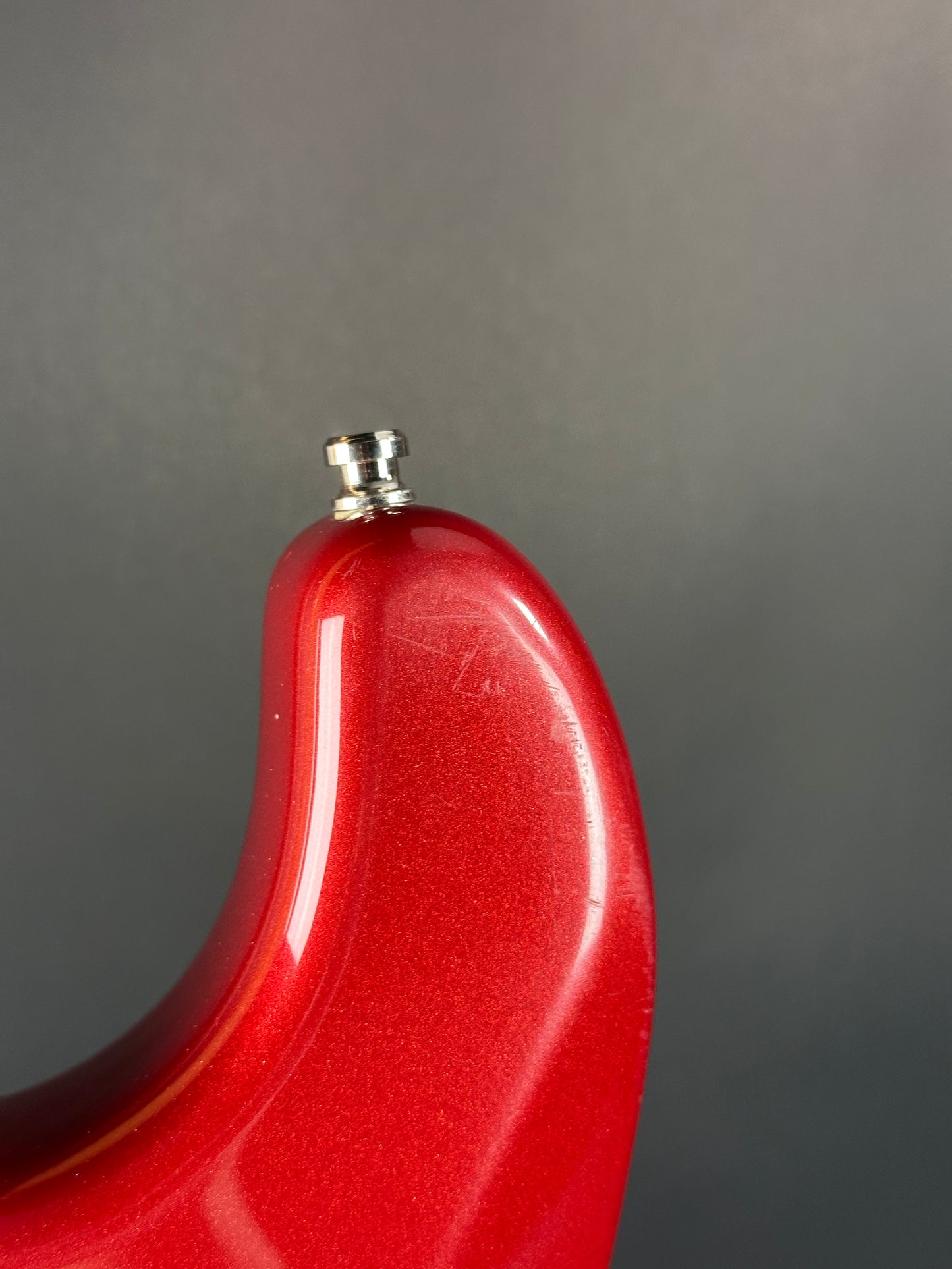 Close-up of a red object with a metallic tip on a gray background