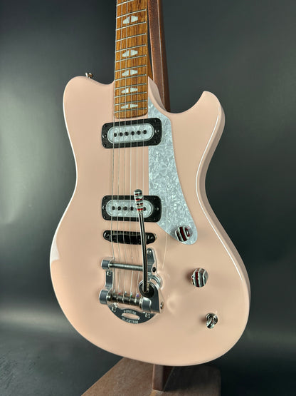 Beige electric guitar with a metallic pickguard on a dark gray background