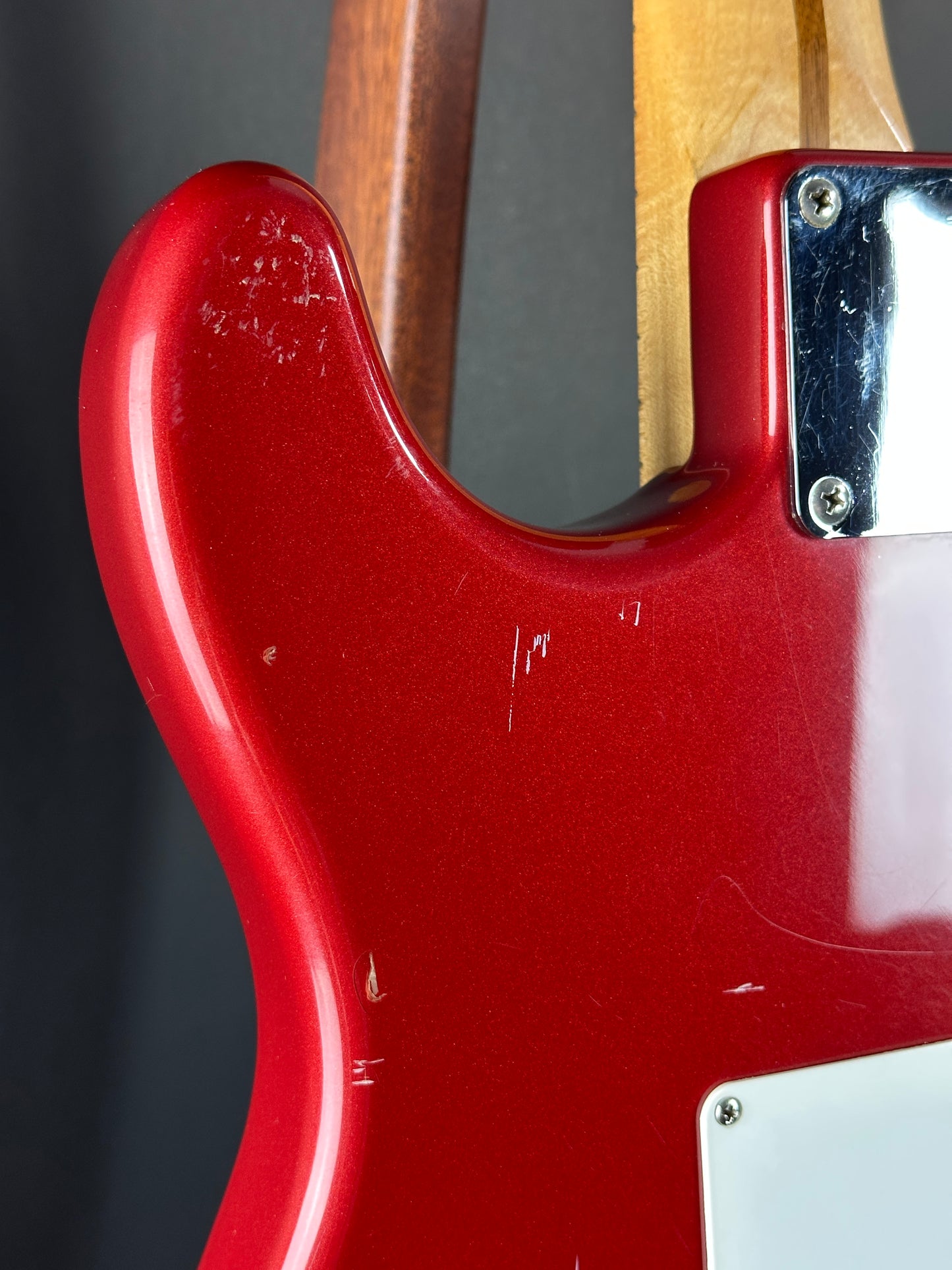 Close-up of a red electric guitar body with a wooden neck.
