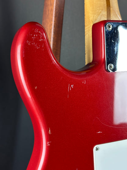 Close-up of a red electric guitar body with a wooden neck.