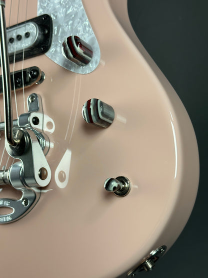 Close-up of a beige electric guitar with metallic hardware on a dark background