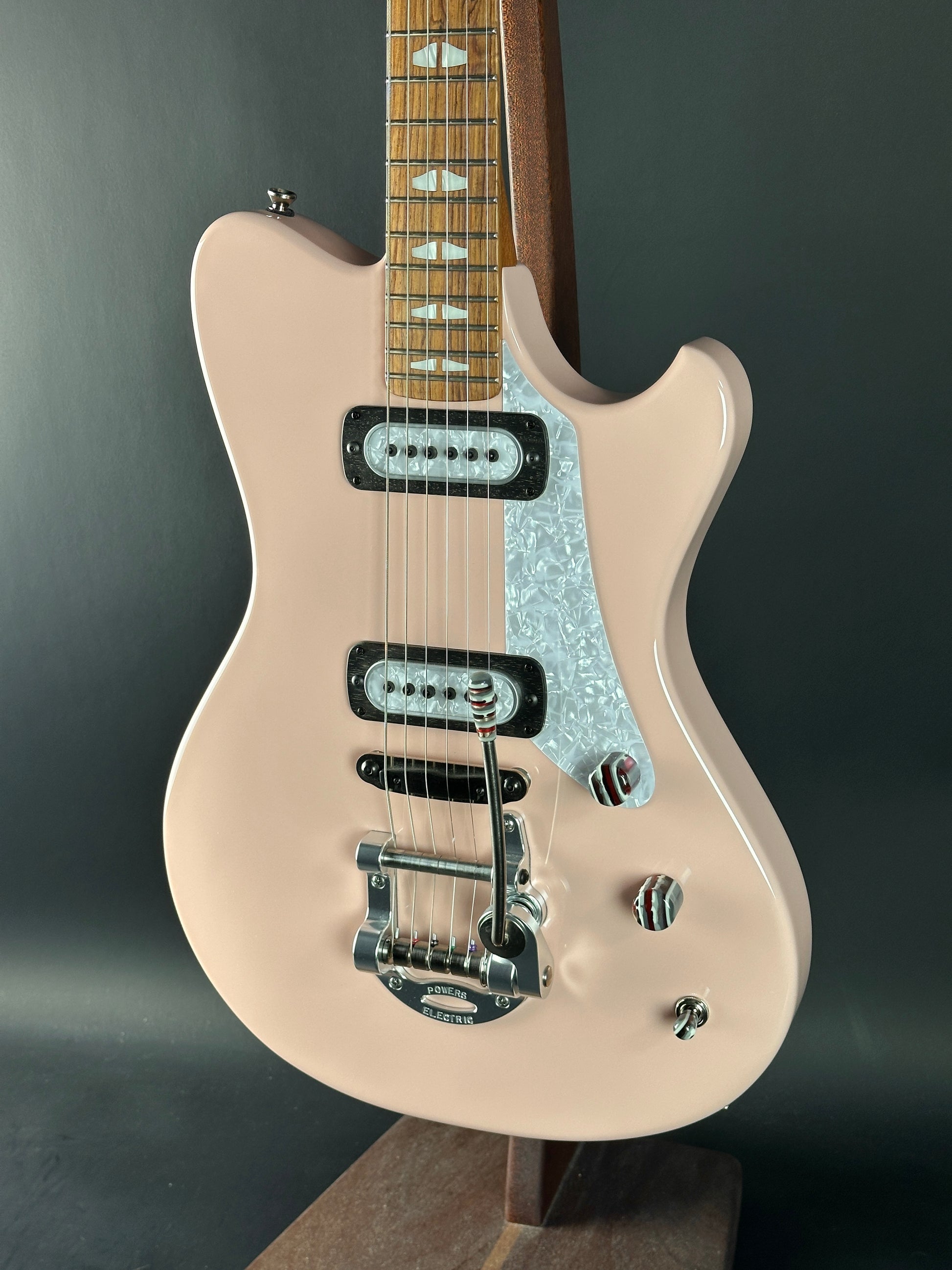 Beige electric guitar with a black pickguard on a dark gray background