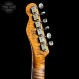 Close-up of the headstock of a Fender electric guitar with a natural wood finish and six silver tuning pegs, shown against a solid black background with a Tone Shop watermark in the top left corner.