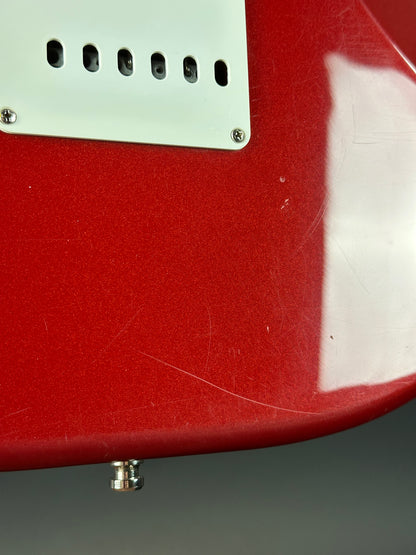 Close-up of a red electric guitar with white pickguard on a gray background
