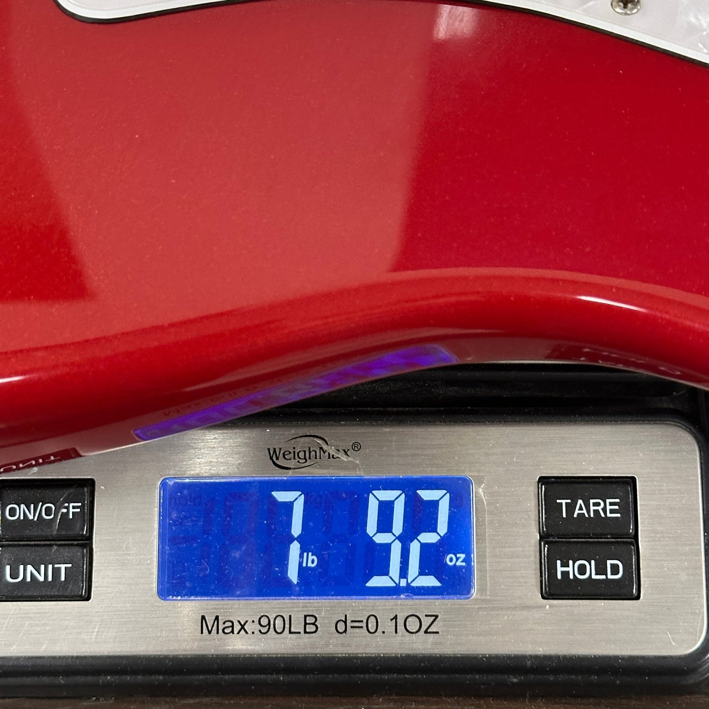 Digital scale displaying weight on a red surface