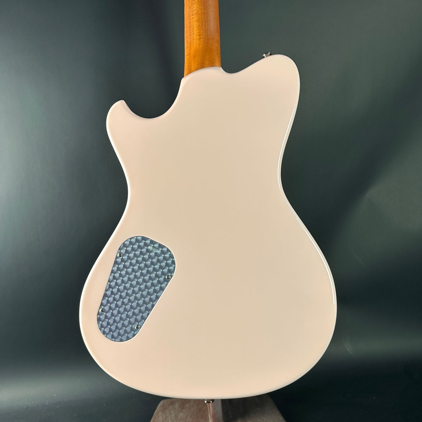 Back view of a cream-colored electric guitar with a dark gray background
