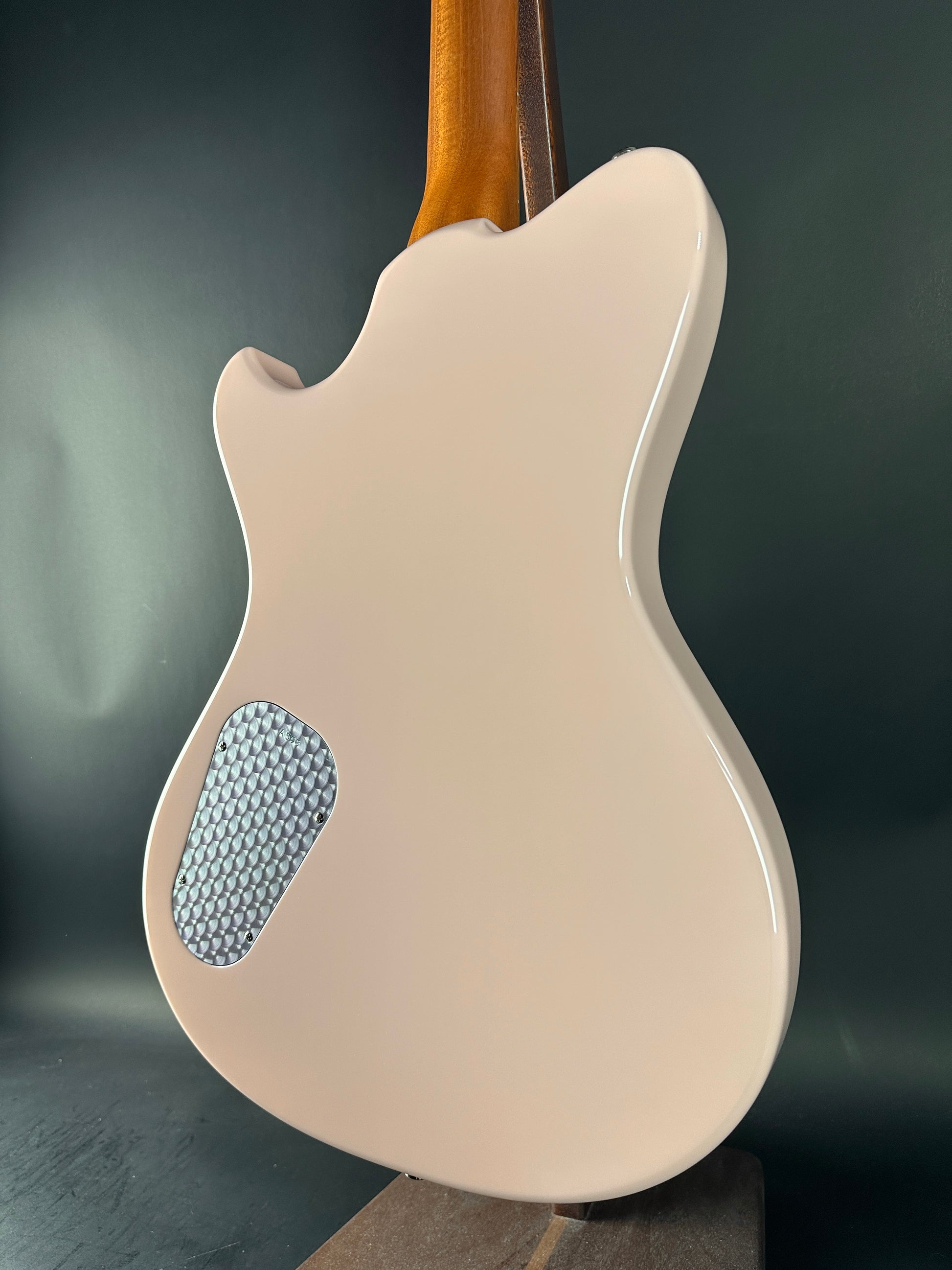 Beige electric guitar with a textured soundhole on a dark background
